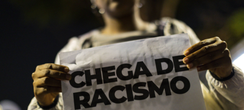 Mulher segura cartaz contra o racismo. Fonte: CSP-Conlutas
